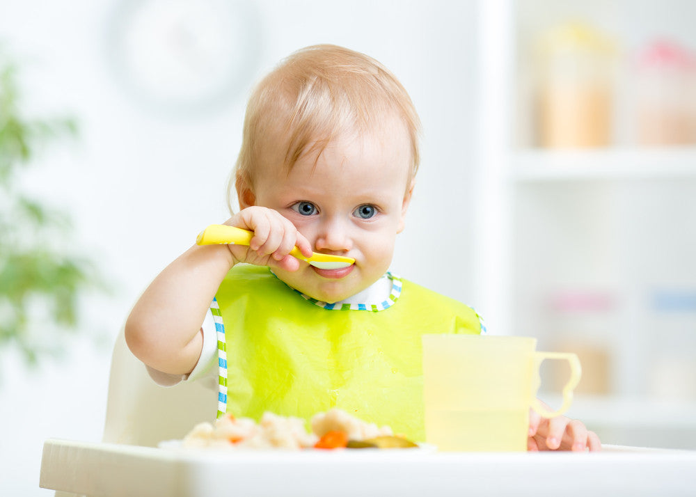 Happy baby eating food in a high chair